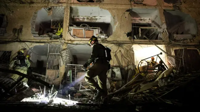 Un soldado israelí utiliza una linterna para inspeccionar los daños tras el impacto de una andanada del ataque iraní en Dimona, el 21 de marzo de 2026.