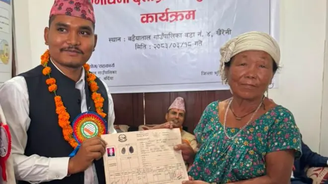 बर्दियामा एक भूमिहीन सुकुम्बासीलाई लालपुर्जा हस्तान्तरण गर्दै एक अधिकारी