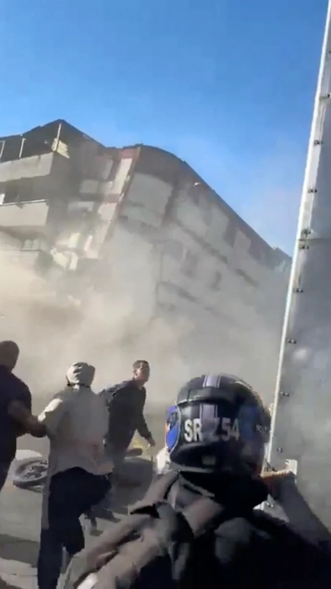Un edificio a punto de colapsar y un grupo de gente de espaldas