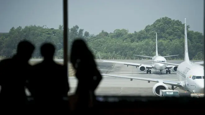 ရန်ကုန်လေဆိပ်မှာ ဆိုက်ကပ်ထားတဲ့လေယာဥ်တွေနဲ့ လေယာဥ်ပေါ် တက်ဖို့ စောင့်ဆိုင်းနေသူတွေ 