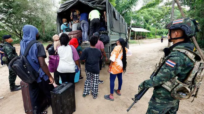 Люди из разных стран, работавшие на территории комплекса KK Park в Мьянме, перебрались в Таиланд через реку Моэй и садятся в автомобиль, пока тайские солдаты несут дежурство в округе Мэсот, провинция Так, 24 октября 2025 года
