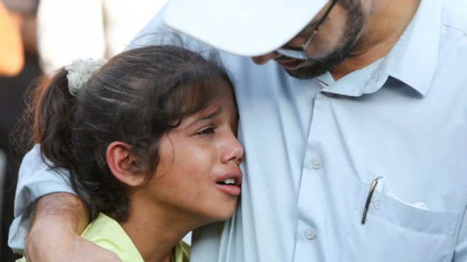 طفلة تبكي وتستند إلى كتف أحد أقاربها في غزة
