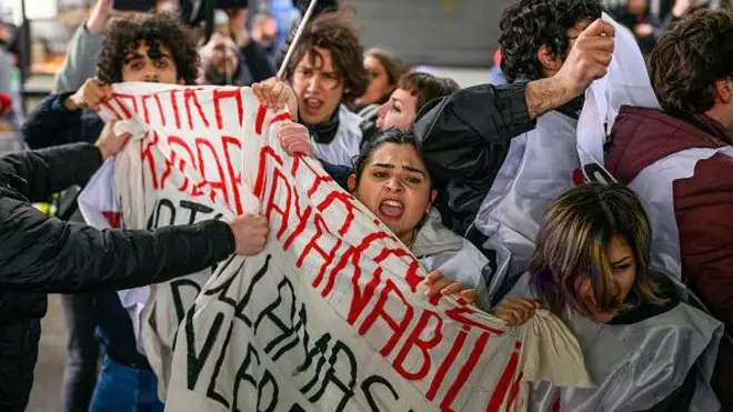 Döviz tutan bir grup şiddetle savruluyor karşısında onları iten eller var. 
