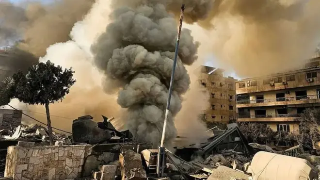 Coluna de fumaça saindo de prédios bombardeados