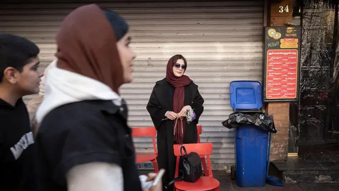 تحمل امرأة إيرانية شابة زهوراً وتقف على رصيف أحد الشوارع في شمال طهران، إيران، في 31 ديسمبر/كانون الأول 2025، في أعقاب أحدث موجة اضطرابات في البلاد. واندلعت احتجاجات في طهران بسبب المشكلات الاقتصادية وانهيار العملة الوطنية. (تصوير: مرتضى نيكوبازل/نورفوتو عبر غيتي إيماجز)