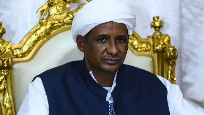 قائد قوات الدعم السريع محمد حمدان دقلو الملقب بحميدتي بملابس تقليدية (جلباب أبيض وصدرية زرقاء) سودانية وعمامة بيضاء
