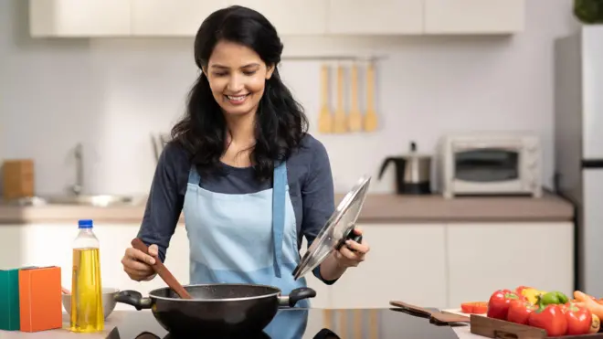 A young man takes a slice of pizza out of the microwave.