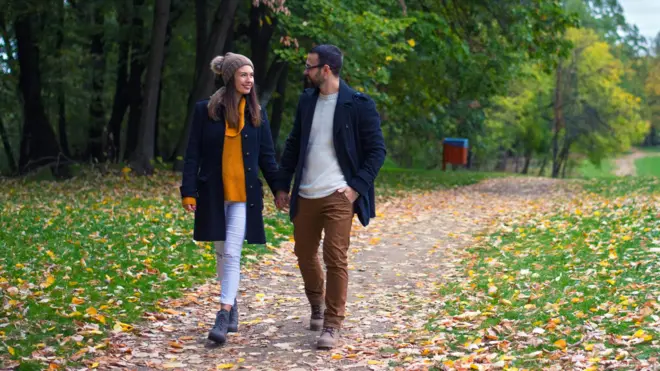 Casal caminhandoestratégia da roletamãos dadasestratégia da roletaparque enquanto sorriem