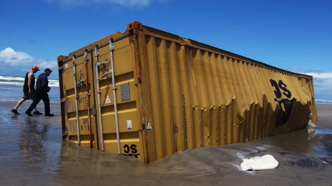 Contêiner em praia, com dois homens caminhando ao lado