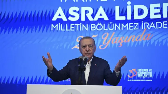 Erdoğan kürsüden konuşuyor, ellerini iki yana açmış.