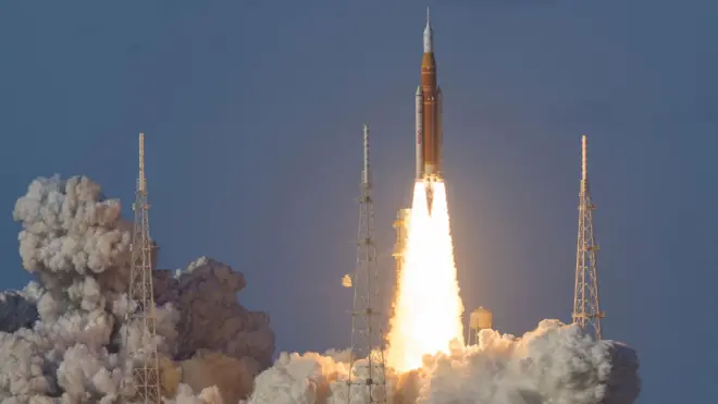 Ракета стартует для полета к Луне, видны клубы дыма и яркий выброс газа из двигателей