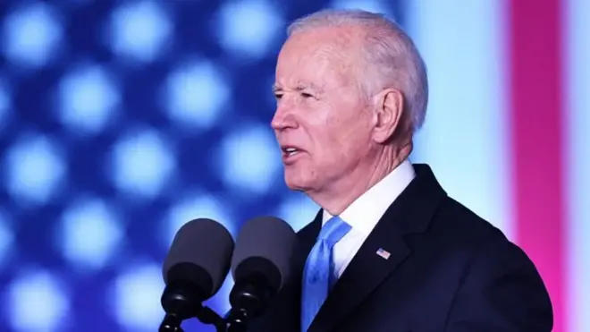 Joe Biden discursando, com bandeira dos EUAsite de apostas tipo blazetelão ao fundo