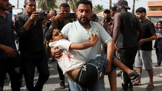 Un Palestinien porte un blessé à l'hôpital des Martyrs d'Al-Aqsa après une frappe israélienne, à Deir Al-Balah, dans le centre de la bande de Gaza, le 17 mai 2025.