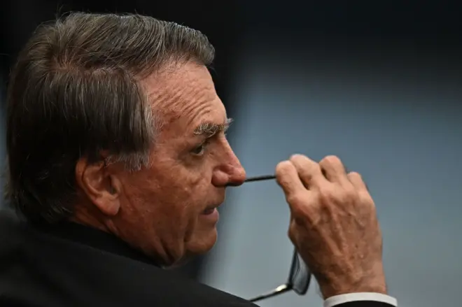 Bolsonaro no STF, olhando para o lado e segurando óculos