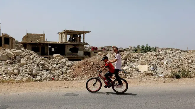 Мальчики на велосипеде на фоне развалин здания