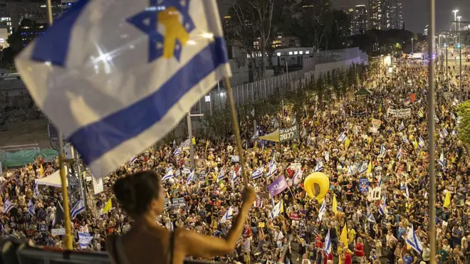 Multitudes de manifestantes portan banderas y pancartas expresando su opinión en Tel Aviv. 
