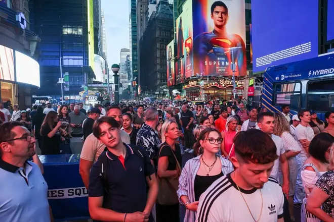 New York, des gens prennent des photos du coucher de soleil sur la 42e rue à Times Square pour admirer ce que l'on appelle le « Manhattanhenge », lorsque le soleil s'aligne parfaitement entre les bâtiments du réseau routier de la ville de New York.