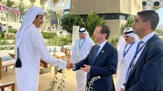 صورة تظهر أمير قطر تميم بين حمد آل ثاني يصافح الرئيس الإسرائيلي إسحاق هرتسوغ خلال لقاء عقد على هامش قمة للمناخ في دبي.