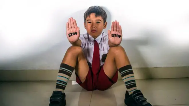 Ilustrasi anak kecil dengan tulisan stop di tangan