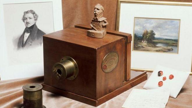 Daguerreótipo do início do século 19 sobre uma mesa com imagens emolduradas ao lado