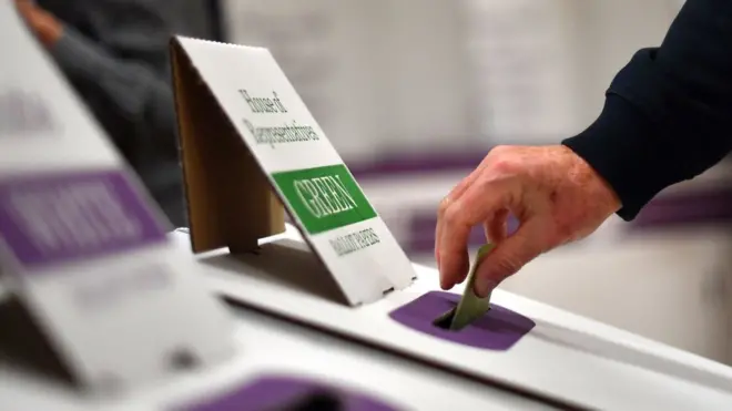 A voter drops her ballot paper into the ballot box during a previous Australian election