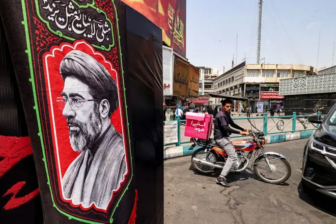 عامل توصيل يقود دراجة نارية بالقرب من صورة المرشد الأعلى الإيراني مجتبى خامنئي في ساحة ولي عصر بوسط طهران.