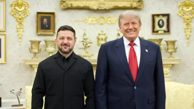 Усміхнені Зеленський і Трамп позують для спільного фото в розкішно оздобленому кабінеті. На задньому плані видно камін, декоративні золотисті елементи інтер’єру, портрети в рамках і моделі літаків.