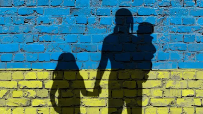 Силуети жінки з дітьми на фоні українського прапора
