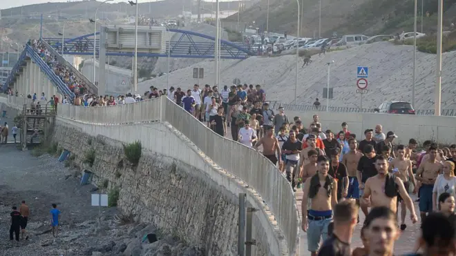 Dozens of migrants walking on a coastal path