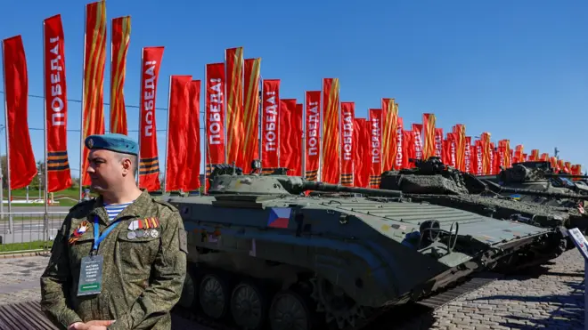 ယူကရိန်းတပ်ဖွဲ့တွေဆီကနေ ရုရှားစစ်တပ်က သိမ်းမိခဲ့တဲ့ မြေပြင်တိုက်ခိုက်ရေးယာဥ်နဲ့ တခြား စစ်ဘက်ဆိုင်ရာပစ္စည်း‌တွေကို ရှင်းပြဖို့ ရပ်နေတဲ့ ရုရှားစစ်သားတစ်ဦး 