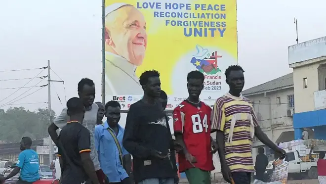 Des jeunes passant davant une affiche du Pape à Djouba