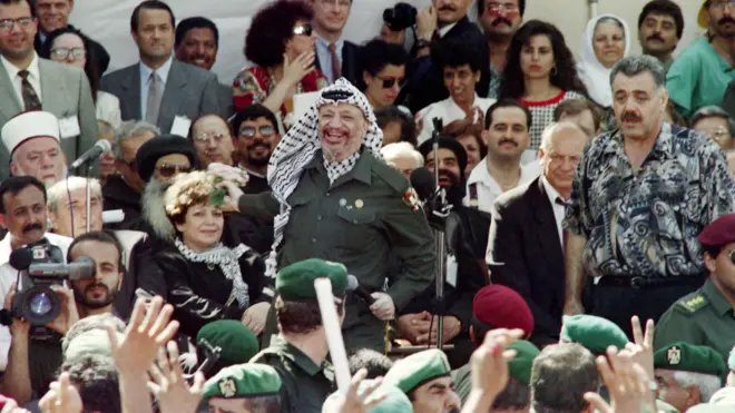 الرئيس الفلسطيني ياسر عرفات يرمي الزهور على حشد مبتهج في 5 يوليو/تموز 1994 بعد وصوله إلى مدينة أريحا