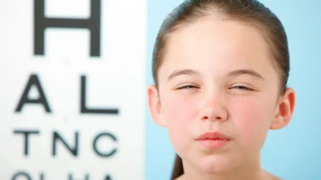 دختر بچهای چشمهایش را تنگ کرده تا بهتر ببیند