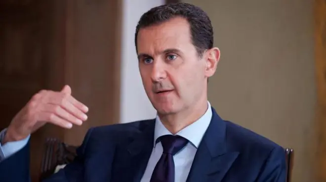 Hoton Bashar al-Assad a shekarar 2016 yana magana yayin da yake sanye da riga mai duhu da farar riga ƴar ciki