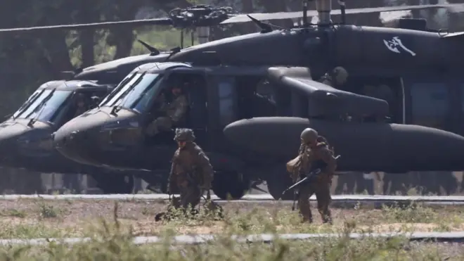 US Marines dressed in camouflage clothing and holding guns take part in training