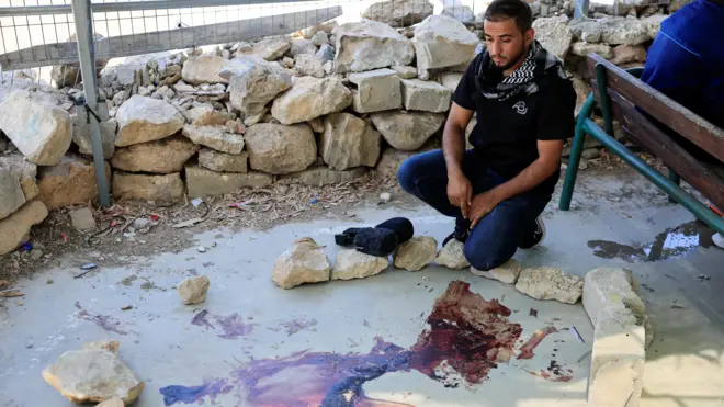 فلسطيني ينظر إلى دماء على الأرض في أعقاب اشتباك مع مستوطن إسرائيلي، في قرية أم الخير، بالقرب من مدينة الخليل في الضفة الغربية المحتلة بتاريخ 29 يوليو/تموز 2025