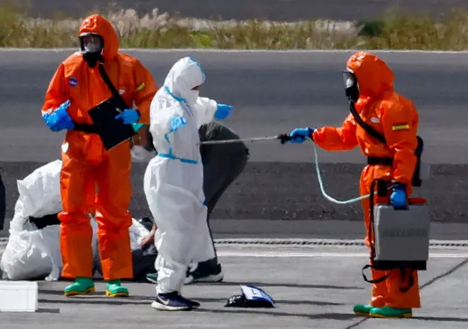 Hantavirüs salgınından etkilenen MV Hondius yolcu gemisinin gelişinin ardından, kişisel koruyucu ekipman giyen kişiler Tenerife Sud havaalanı pistinde hazırlık yapıyor.
