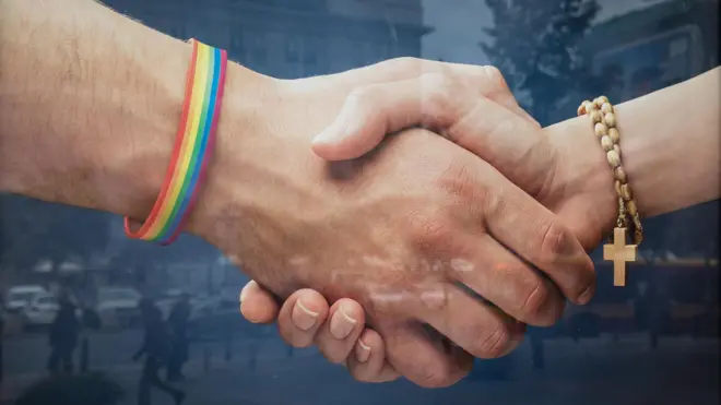 dos personas se estrechan la mano. Una con un rosario y la otra con una bandera lgbt