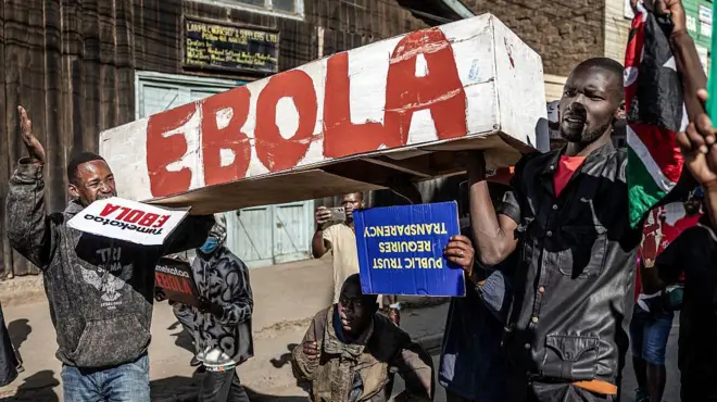 Abari mu myiyerekano batwaye isandugu. Ku ruhande rwayo handitsweko ijambo "Ebola", mu ndome nini zitukura. Bafise n'ivyapa vyanditsweko amajambo y'Igiswahili, asobanura ati: "turiyamirije Ebola", bikabandanya biti: "Ubwizigirwa bwa reta buvana n'ingene ikorera ku mugaragaro".