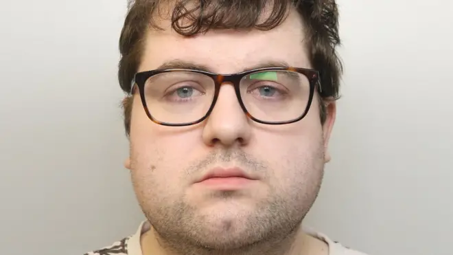 Фотографія Натана Беннета під час суду. На ньому коричневі окуляри. Він має каштанове волосся середньої довжини. На ньому кремова футболка з коричневим візерунком у формі листя.