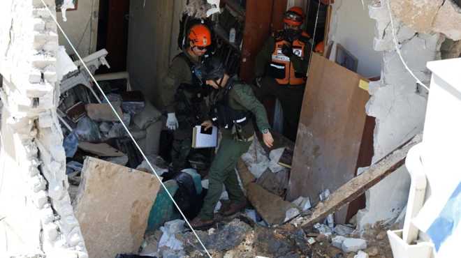 Tres soldados vestidos de verde y con cascos caminan por los escombros de un edificio