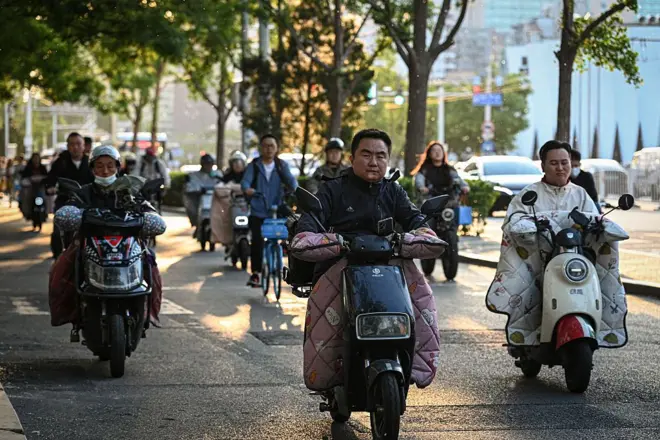 Pessoas dirigindo scooter elétrica em Pequim