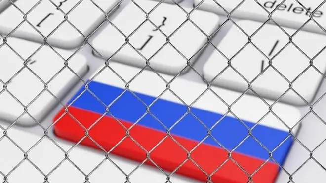 یک کیبورد که روی یکی از کلیدها پرچم روسیه است، نزدیک به کلید حدف، کل کیبورد پشت یک حصار سیمی است