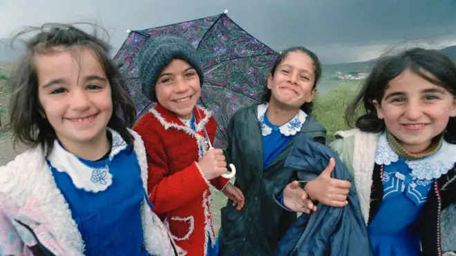 Mavi önlüklü dört kız çocuğu, kameraya gülümsüyorlar