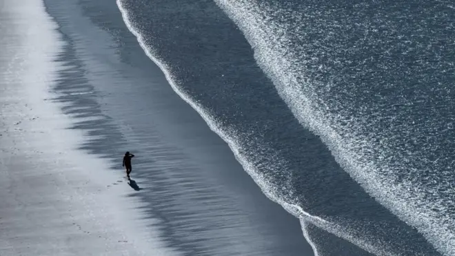 شخص يمشي وحيداً على الشاطئ