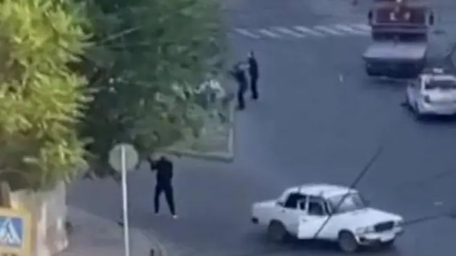 কালো পোশাক পরা একদল লোক পুলিশকে লক্ষ্য করে গুলি ছুড়ছে