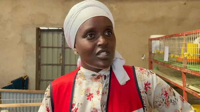 Umukobwa yambaye igitambara ku mutwe, n'iburuzi ifise indabyo, hejuru yambaye aga-singlet