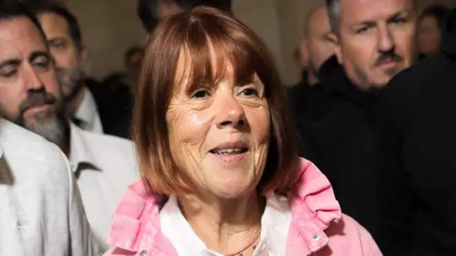 Gisèle Pelicot con una sonrisa rodeada de hombres a la salida de la corte