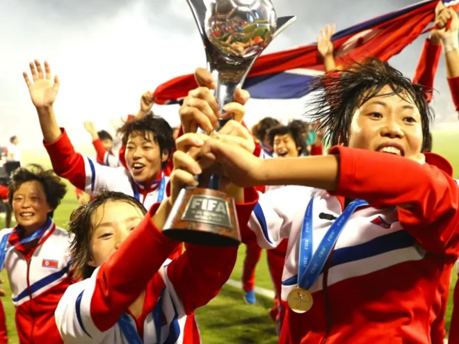 북한 축구 선수들이 트로피를 들고 환호하고 있다