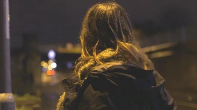 Mulher de costas olha para luzes coloridas ao fundo